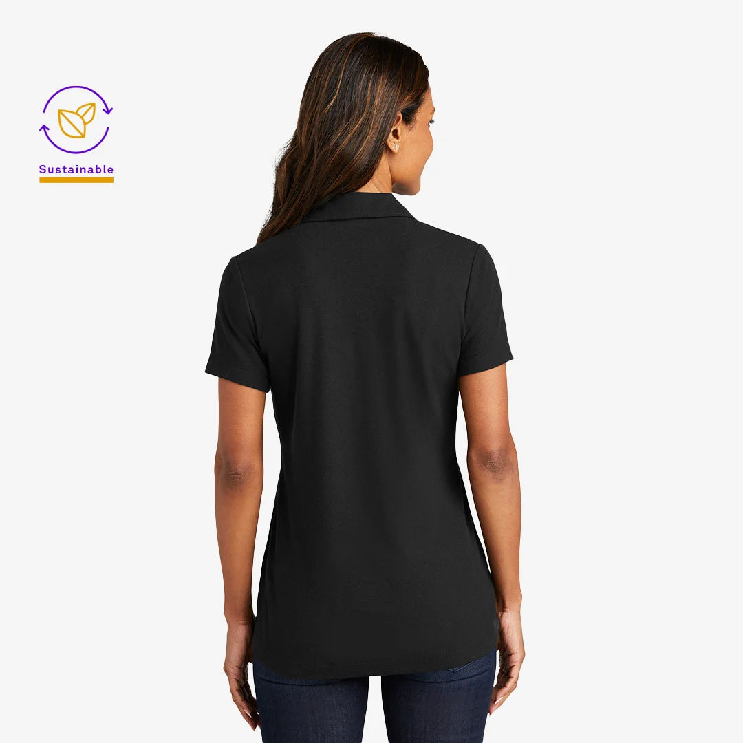 Woman wearing Port Authority Women's C-FREE Cotton Blend Pique Polo Shirt in Black Back - LK867